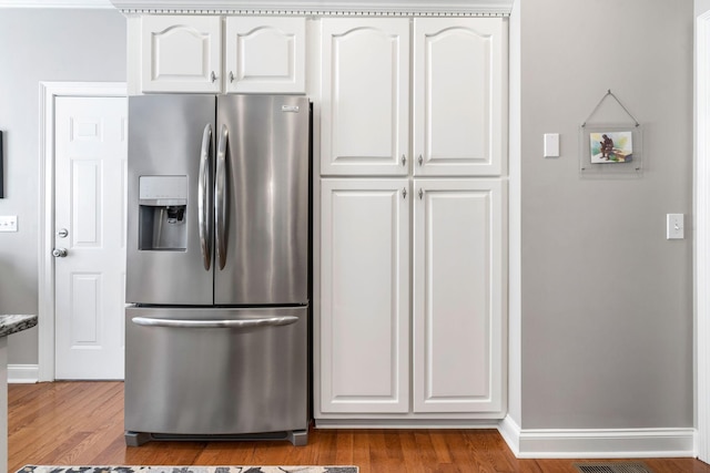 kitchen with white cabinetry, stainless steel refrigerator with ice dispenser, and light hardwood / wood-style flooring