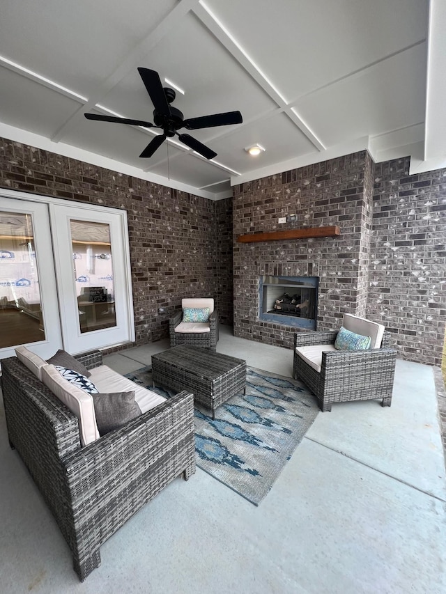 living room featuring brick wall, an outdoor brick fireplace, and ceiling fan