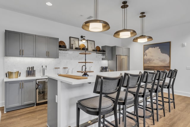 kitchen with light wood-type flooring, beverage cooler, pendant lighting, gray cabinets, and high end refrigerator