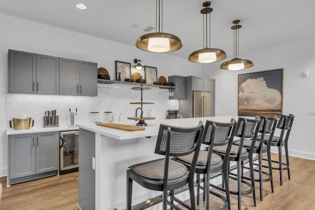 kitchen featuring gray cabinets, light wood-style flooring, light countertops, decorative backsplash, and high end refrigerator