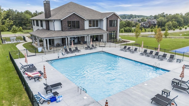 community pool featuring a patio area, fence, and a lawn