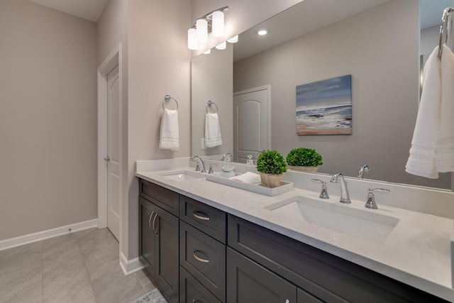 bathroom featuring tile patterned floors, double vanity, baseboards, and a sink