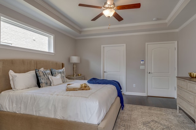 bedroom featuring ornamental molding, ceiling fan, dark wood-type flooring, and a raised ceiling