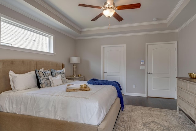 bedroom featuring ornamental molding, baseboards, a raised ceiling, and wood finished floors