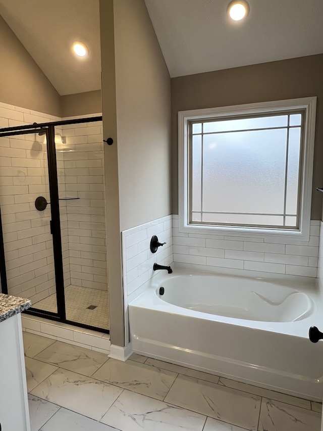 bathroom with a healthy amount of sunlight, vaulted ceiling, vanity, and independent shower and bath