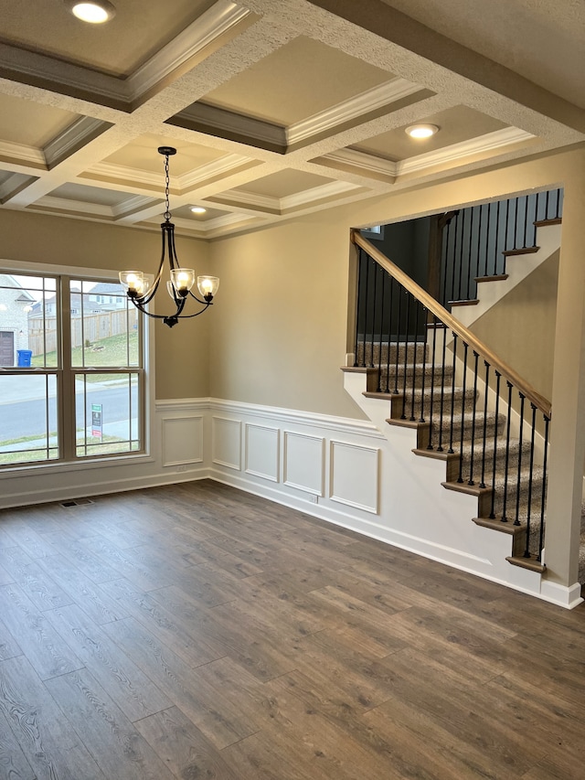 spare room with crown molding, an inviting chandelier, dark hardwood / wood-style flooring, and coffered ceiling