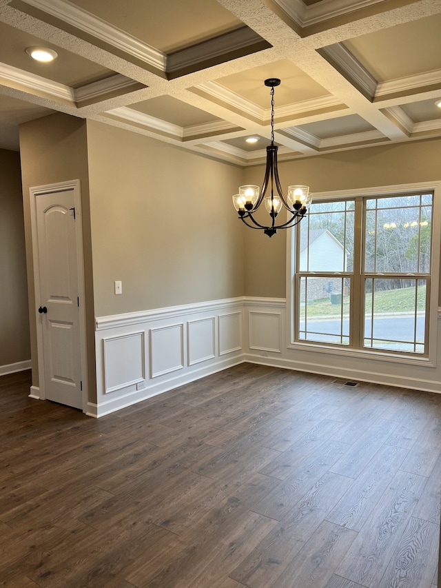 empty room featuring ornamental molding, dark hardwood / wood-style flooring, coffered ceiling, and a chandelier