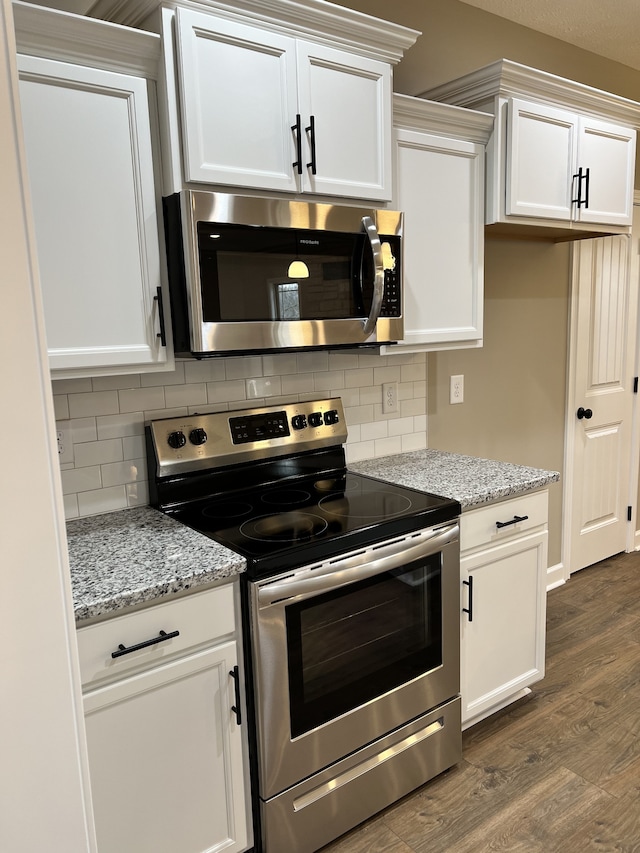 kitchen featuring appliances with stainless steel finishes, light stone counters, white cabinetry, and dark hardwood / wood-style floors