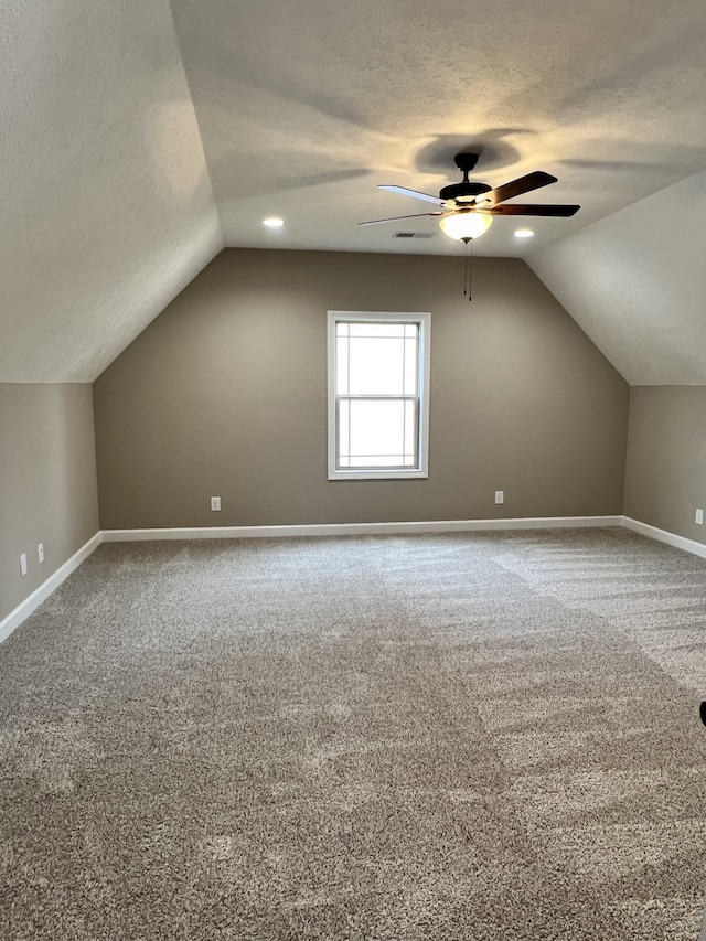 additional living space with a textured ceiling, carpet, ceiling fan, and vaulted ceiling