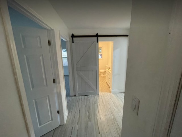 hall with a barn door and light hardwood / wood-style floors