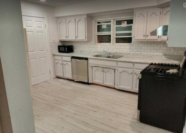 kitchen featuring wall chimney range hood, stainless steel dishwasher, range, and white cabinetry