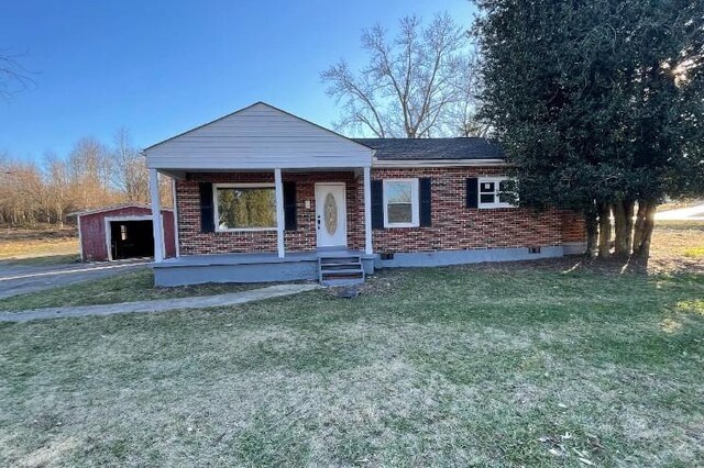 view of front of house featuring a front yard, a garage, an outbuilding, and a porch