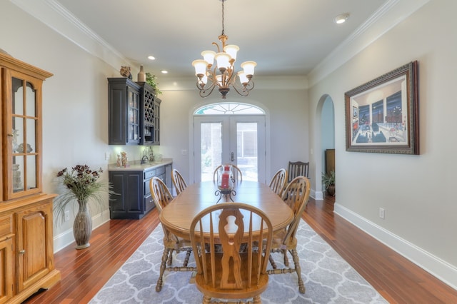 dining space featuring crown molding, french doors, an inviting chandelier, and dark wood-type flooring