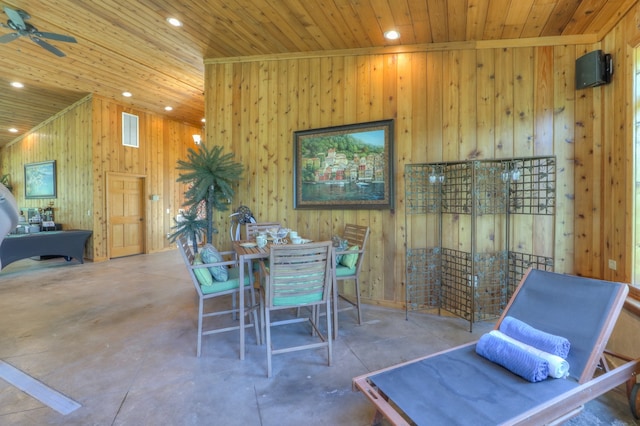 dining space featuring wooden walls, concrete floors, ceiling fan, and wood ceiling