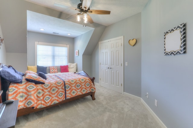 carpeted bedroom featuring ceiling fan, a textured ceiling, lofted ceiling, and a closet