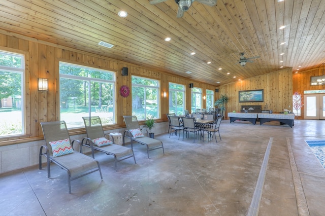 interior space featuring french doors, wooden walls, ceiling fan, wood ceiling, and concrete floors