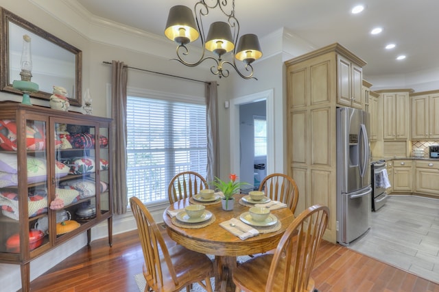 dining area with light wood-type flooring, crown molding, a wealth of natural light, and a chandelier