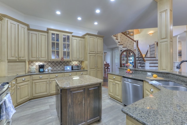 kitchen featuring appliances with stainless steel finishes, sink, dark stone countertops, a center island, and ornate columns