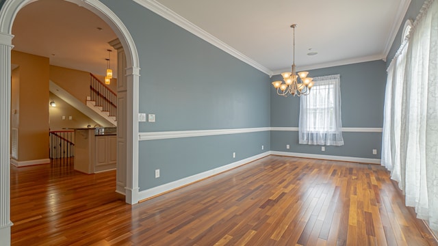 empty room with an inviting chandelier, dark hardwood / wood-style flooring, and ornamental molding