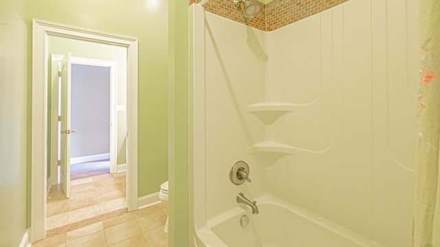 bathroom with shower / tub combo, toilet, and tile floors