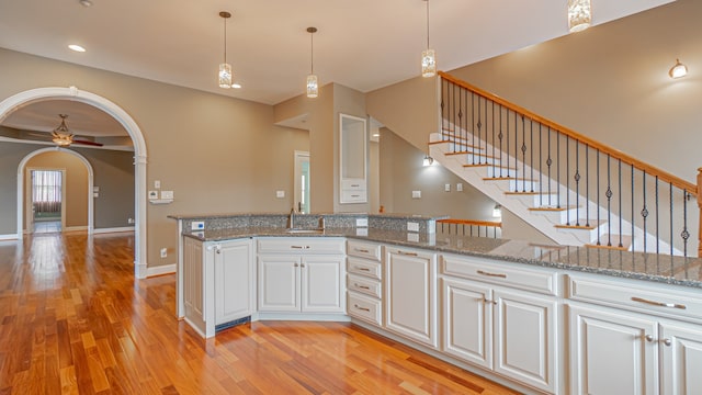 kitchen featuring white cabinets, light stone countertops, ceiling fan, and light wood-type flooring