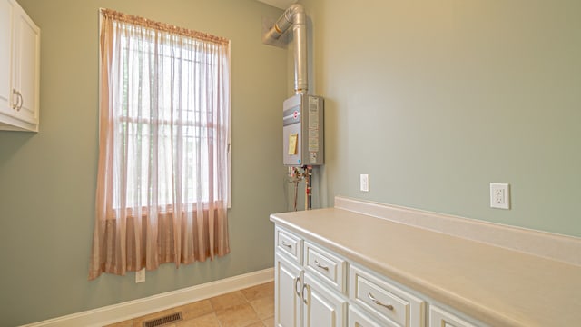 bathroom featuring vanity, tankless water heater, a healthy amount of sunlight, and tile floors