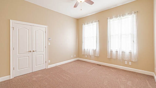 unfurnished bedroom with ceiling fan, multiple windows, light carpet, and a closet