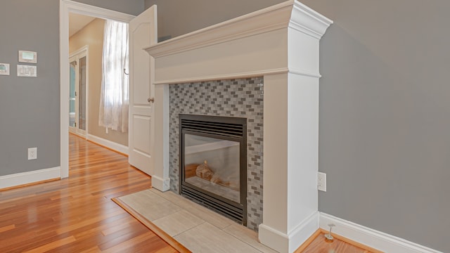 unfurnished living room featuring a tiled fireplace and light hardwood / wood-style flooring