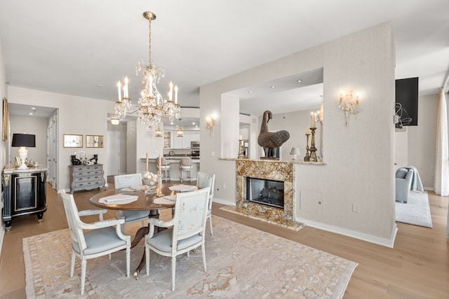 dining space with a fireplace, a chandelier, and light wood-type flooring