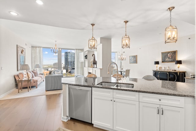 kitchen featuring hanging light fixtures, light hardwood / wood-style floors, white cabinets, dark stone counters, and dishwasher