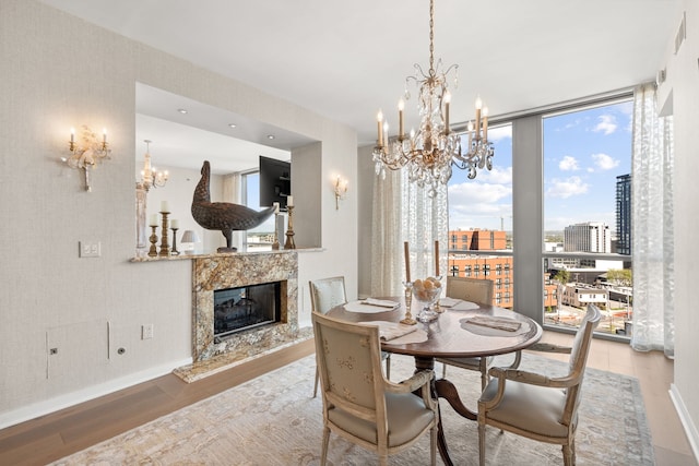 dining space with light hardwood / wood-style flooring, a fireplace, a chandelier, and a healthy amount of sunlight