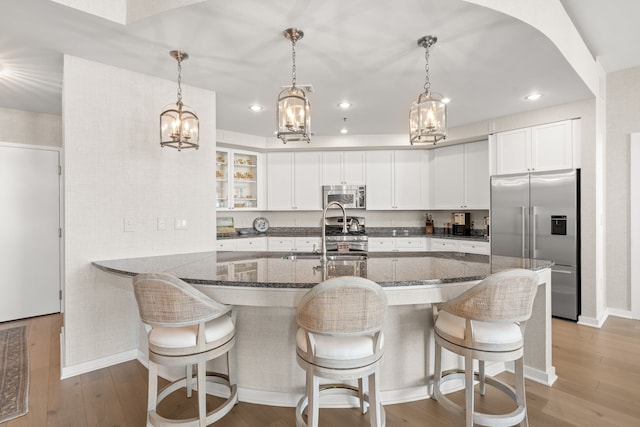 kitchen featuring stainless steel appliances, white cabinetry, dark stone countertops, and light hardwood / wood-style floors