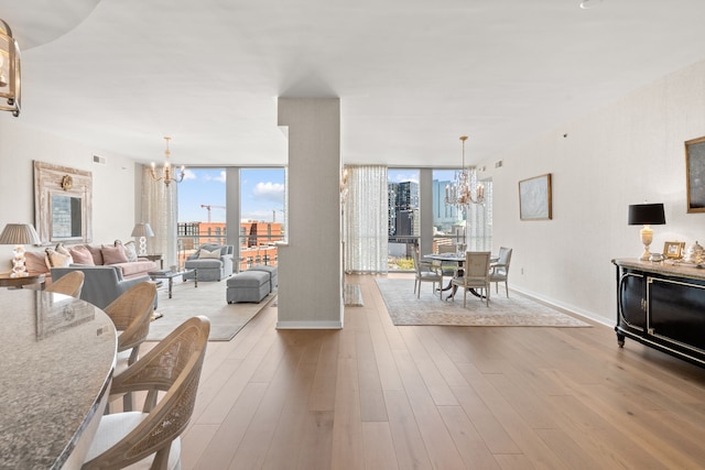 living room with an inviting chandelier, floor to ceiling windows, and light hardwood / wood-style flooring