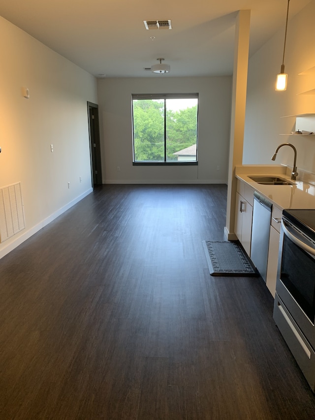 kitchen with white cabinetry, dark hardwood / wood-style floors, sink, stainless steel appliances, and pendant lighting