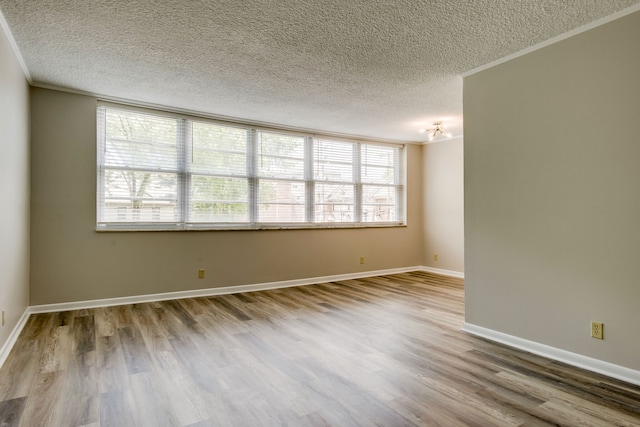 empty room with crown molding, a textured ceiling, and hardwood / wood-style flooring