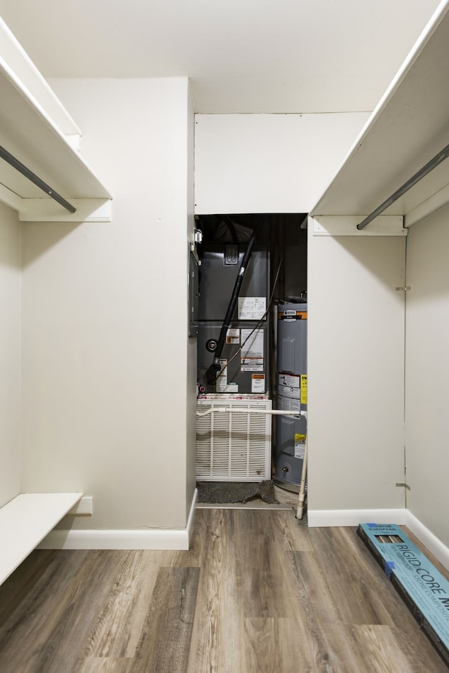 spacious closet featuring light hardwood / wood-style flooring, heating utilities, and water heater