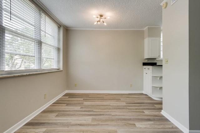 spare room featuring light hardwood / wood-style floors, a textured ceiling, and crown molding