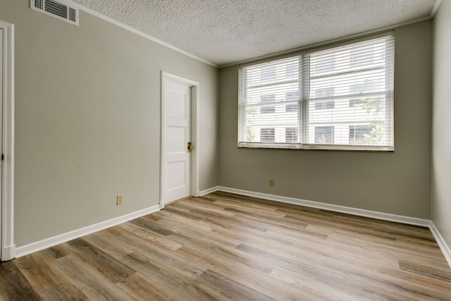 empty room featuring crown molding, light hardwood / wood-style floors, and a textured ceiling