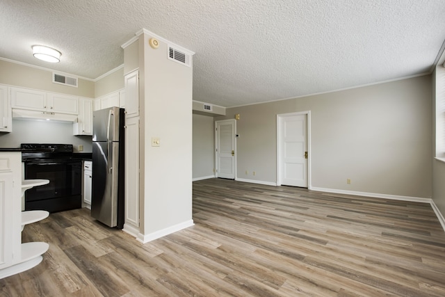 kitchen featuring light hardwood / wood-style flooring, a textured ceiling, stainless steel refrigerator, and black electric range oven