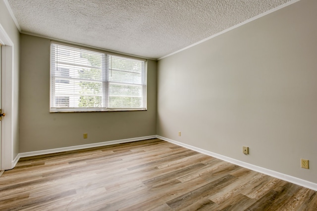 empty room with a textured ceiling, ornamental molding, and light hardwood / wood-style floors