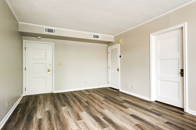 spare room featuring a textured ceiling, dark hardwood / wood-style floors, and ornamental molding