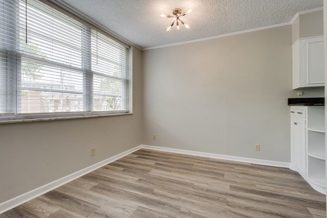 unfurnished dining area featuring a textured ceiling, a chandelier, light hardwood / wood-style floors, and crown molding