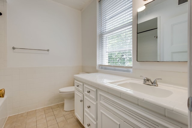 bathroom featuring tile walls, tile flooring, toilet, and vanity