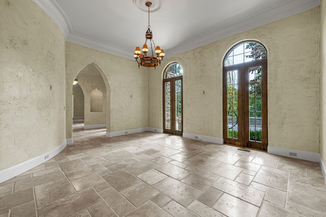 foyer entrance with a chandelier, ornamental molding, and french doors