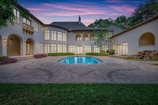 pool at dusk with french doors and a patio