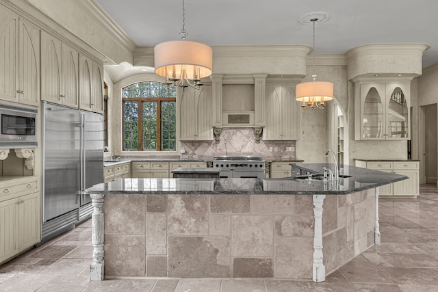 kitchen with built in appliances, a kitchen island with sink, and a notable chandelier