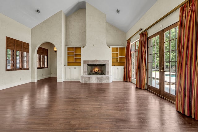 unfurnished living room featuring high vaulted ceiling, built in shelves, dark hardwood / wood-style floors, and french doors