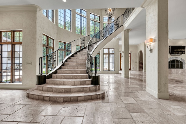 stairs featuring french doors, crown molding, a towering ceiling, and an inviting chandelier