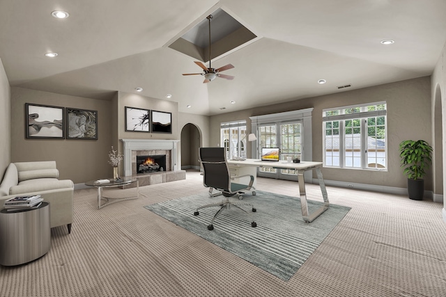 home office with ceiling fan, a tile fireplace, light carpet, and vaulted ceiling