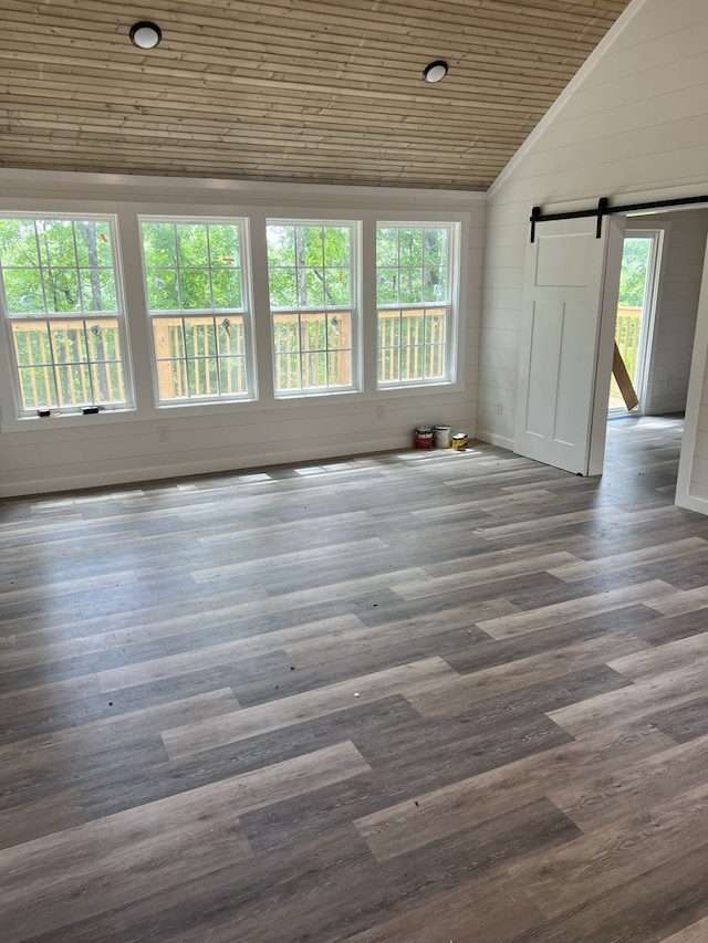 empty room with a barn door, dark hardwood / wood-style floors, and a wealth of natural light